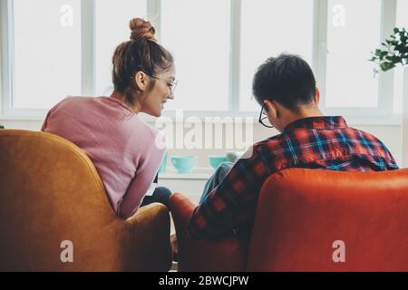 Caucasian business couple working from home at the laptop in the armchair while wearing eyeglasses using laptop Stock Photo