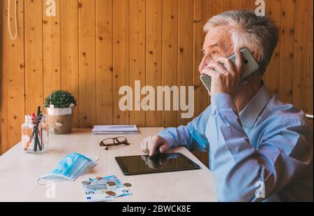 Concerned businessman talks on the phone about the economic impact of coronavirus, the economic crisis in international markets. Senior man talking Stock Photo