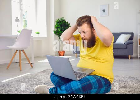 Shocked man reading news on laptop in room Stock Photo