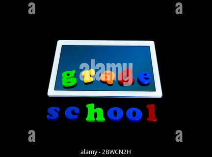 Tablet with the inscription GRADE and SCHOOL. Tablet PC, technology and education. Levitation, black background.Back to school concept Stock Photo