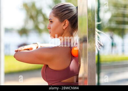 Young athlete woman in tight top leaning on small ball to fix back ache, massaging stiff muscles and sore neck, exercise to relieve spinal pain, hurti Stock Photo