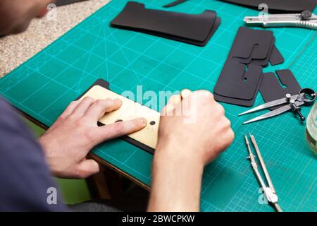 Leather Craftsman working with leather. Making a wallet. Stock Photo
