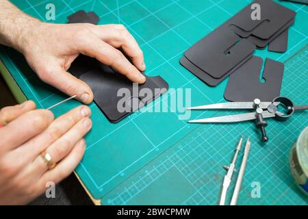 Leather Craftsman working with leather. Making a wallet. Stock Photo