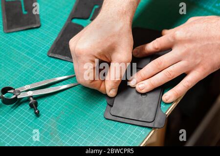 Leather Craftsman working with leather. Making a wallet. Stock Photo