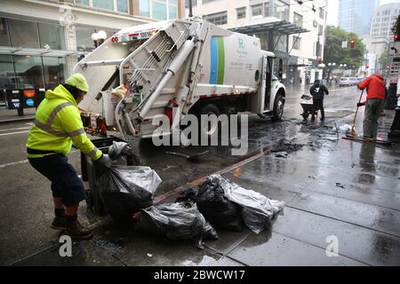Seattle, WA, USA. 31st May, 2020. Sanitation workers and volunteers clean up debris from a car that had been set on fire during a riot the previous night on May 31, 2020 in Seattle, Washington. Protests erupted nationwide after the death of George Floyd who died while in the custody of a policeman who knelt on his neck in Minneapolis. Credit: Karen Ducey/ZUMA Wire/Alamy Live News Stock Photo