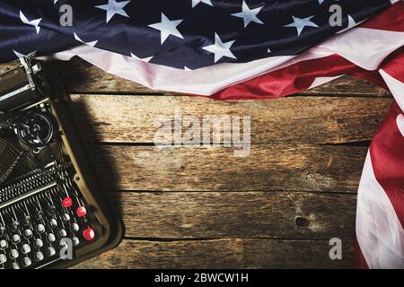 Old retro typewriter and the flag of the United States of America on a wooden table Stock Photo