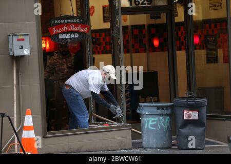 Seattle, WA, USA. 31st May, 2020. A volunteer cleans up damage to a restaurant early in the morning after rioters, expressing outrage over the death of George Floyd, vandalized stores and burned cars the previous night on May 31, 2020 in Seattle, Washington. Protests erupted nationwide after Floyd died while in the custody of a policeman who knelt on his neck in Minneapolis. Credit: Karen Ducey/ZUMA Wire/Alamy Live News Stock Photo
