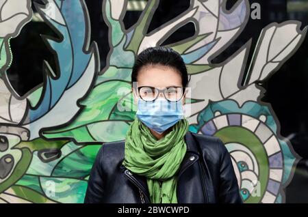 medical mask and safety glasses on a female face, protective equipment, close-up Stock Photo