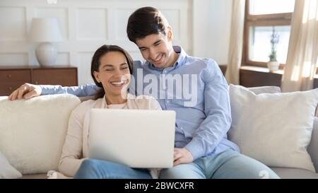Smiling young couple relax at home using laptop together Stock Photo