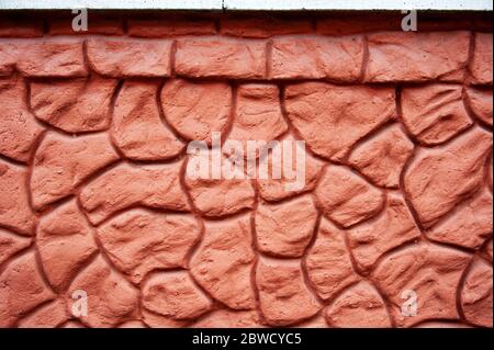 Decorative imitation of a pebble stone wall background texture. The cement plaster of the wall is decorated with large round pebbles. Finishing the fa Stock Photo