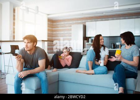 Big family is sitting on the sofa. Everyone is busy with his own business. Stock Photo