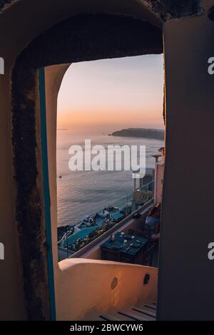 View of the caldera of Santorini through a gate of a restaurant at the top of Oia Stock Photo