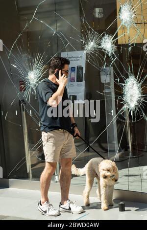 Charleston, United States. 31st May, 2020. A pedestrian stops to view the shattered glass store front of the Apple Store on the King Street shopping district after a protest over the death of George Floyd, turned violent and destructive May 31, 2020 in Charleston, South Carolina. Floyd was choked to death by police in Minneapolis resulting in protests sweeping across the nation. Credit: Richard Ellis/Alamy Live News Stock Photo