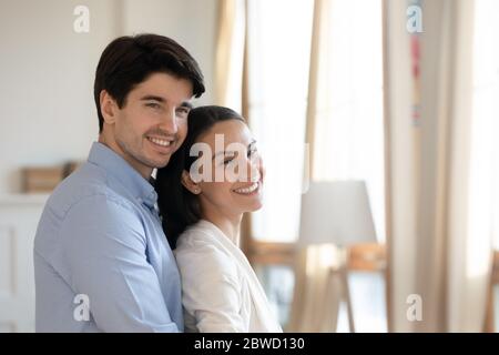 Happy young couple stand in new home hugging Stock Photo