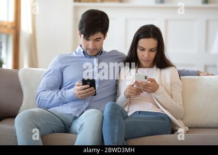 Young couple relax on couch using modern smartphones Stock Photo