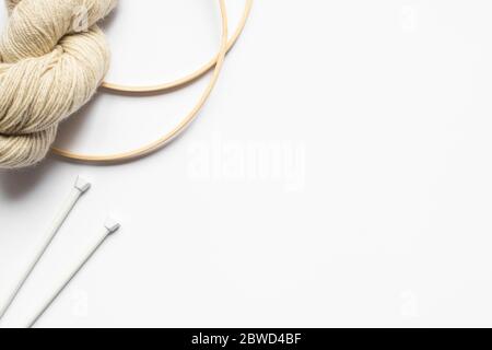 top view of beige yarn and knitting needles and looms on white background with copy space Stock Photo