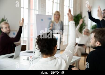Back rear focus on young indian female employee raising hand. Stock Photo