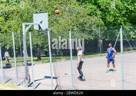 Young adults playing basketball on Sunny day Stock Photo