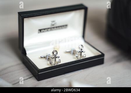 Close up of shiny anchor cufflinks in black padded box. Light background. Stock Photo