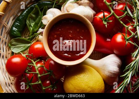 top view of delicious tomato sauce with fresh ripe vegetables in basket Stock Photo