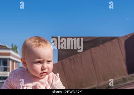 Close up of cute baby girl wear adorable dress on the roof, soap bubbles floating around, little girl trying to catch the bubbles Stock Photo