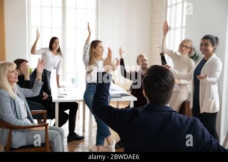 Happy different ages business people raising hands, having questions. Stock Photo