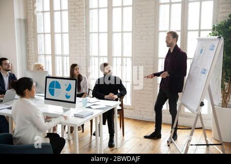 Young male team leader presenting marketing research results to colleagues. Stock Photo