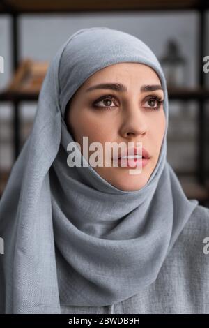 Depression concept. Upset muslim woman in hijab crying on sofa at home ...