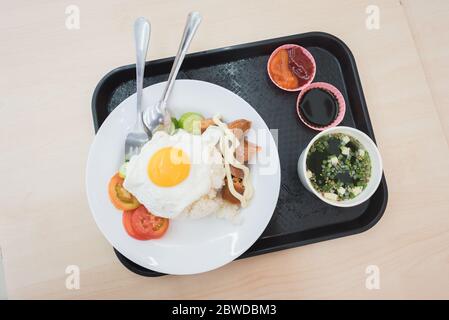 Meal at convenience store's canteen: fried egg and rice, a sausage, seaweed soup & fresh veggies. A closeup, a top-down view of plates on a tray. Stock Photo