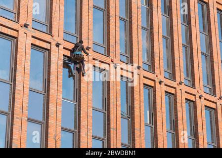 Rope access technician works on highrise building's facade. Stock Photo