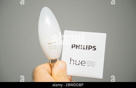 Paris, France - Aug 7, 2019: Man hand holding instruction manual and new internet connected Philips Hue E14 color and white ambiance bulb Stock Photo