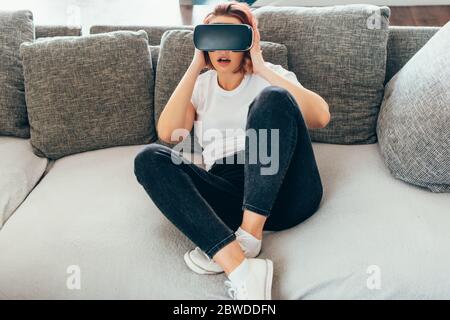 surprised girl using virtual reality headset at home on quarantine Stock Photo