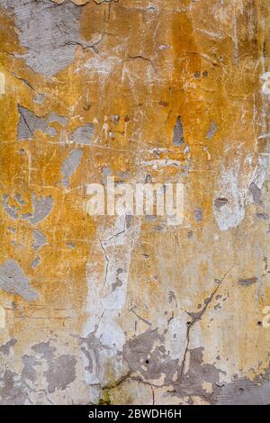 Damaged distressed concrete wall with large cracks. Texture of old white and yellow cement wall with cracks Stock Photo