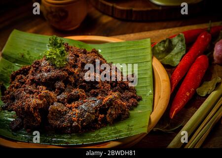 Rendang Paru or Spicy Beef Lung stew traditional food from Padang, Indonesia. The dish is arranged among the spices and herbs Stock Photo