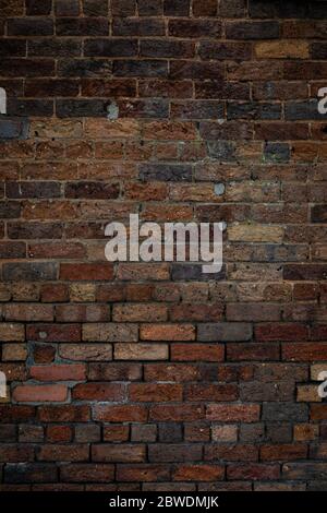 Dark brick wall texture featuring a variety of mixed bricks in many colors, backdrop for creative copy space, vertical aspect Stock Photo