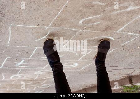 Kid playing hopscotch on playground outdoors, children outdoor activities. Stock Photo