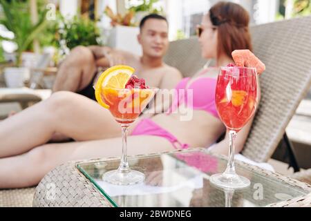 Delicious fruit smoothies on small table next to chaise-lounges of spa hotel Stock Photo