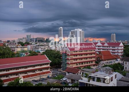 At sunset, dark monsoon clouds hang over Phra Nakhon area in Bangkok, Thailand, the buildings of (temple) Wat Sam Phraya in the foreground Stock Photo