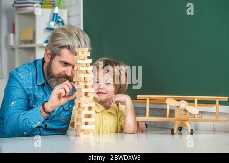 Playing Jenga. Pupils Education. Cute little preschool kid boy with teacher playing in a classroom. Learning and education concept. Stock Photo