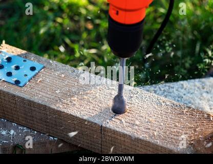 Making holes in a pine beam using an electric drill with wood drilling bit Stock Photo