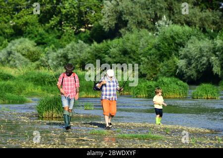 Grandson with father and grandfather fishing by lake. Old and young. Father and son fishing. Man in different ages. Stock Photo