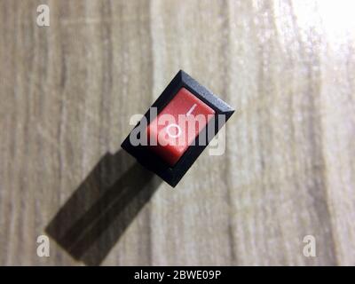 Close up of On-Off switch on wooden background. Top view of red on/of switch. Stock Photo