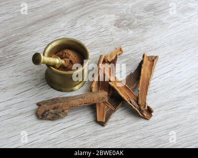 powder and cinnamon sticks mortar with pestle isolated on wooden background Stock Photo