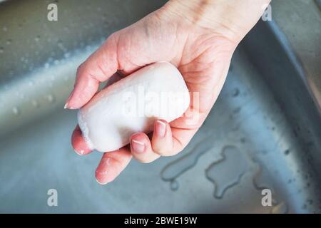 woman holds soap in her hand over the sink. concept treating the skin of hands from viruses and microbes Stock Photo