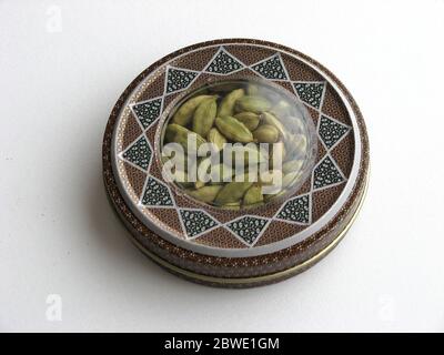 Mashhad, IRAN, 01 03 2020: Close up of green cardamom pods into handcraft box on white background. Iran souvenir. Aromatic spice. Stock Photo