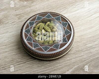 mashhad, IRAN, 01 03 2020: Green cardamom pods into handcraft box on wooden background. Iran souvenir. Aromatic spice. Stock Photo