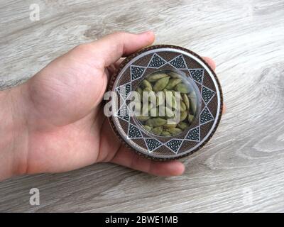 Mashhad, IRAN, 01 03 2020:  Green cardamom pods into handcraft box in male hand. Stock Photo