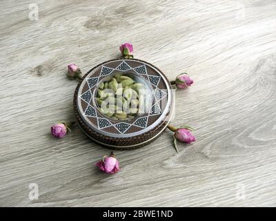 mashhad, IRAN, 01 03 2020: Green cardamom pods into beautiful handcraft box with flower decoration on wooden background. Stock Photo