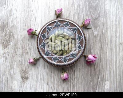 Mashhad, IRAN, 01 03 2020: Beautiful handcraft box with cardamom pods  with flower decoration on wooden background. Aromatic spice. Stock Photo
