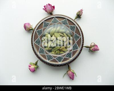 mashhad, IRAN, 01 03 2020: Green cardamom pods into beautiful handcraft box with flower decoration on white background. Stock Photo